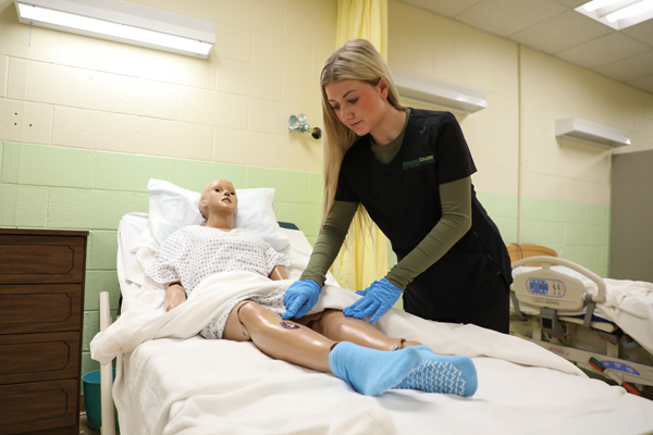 CNA student performing tests on a mannequin.