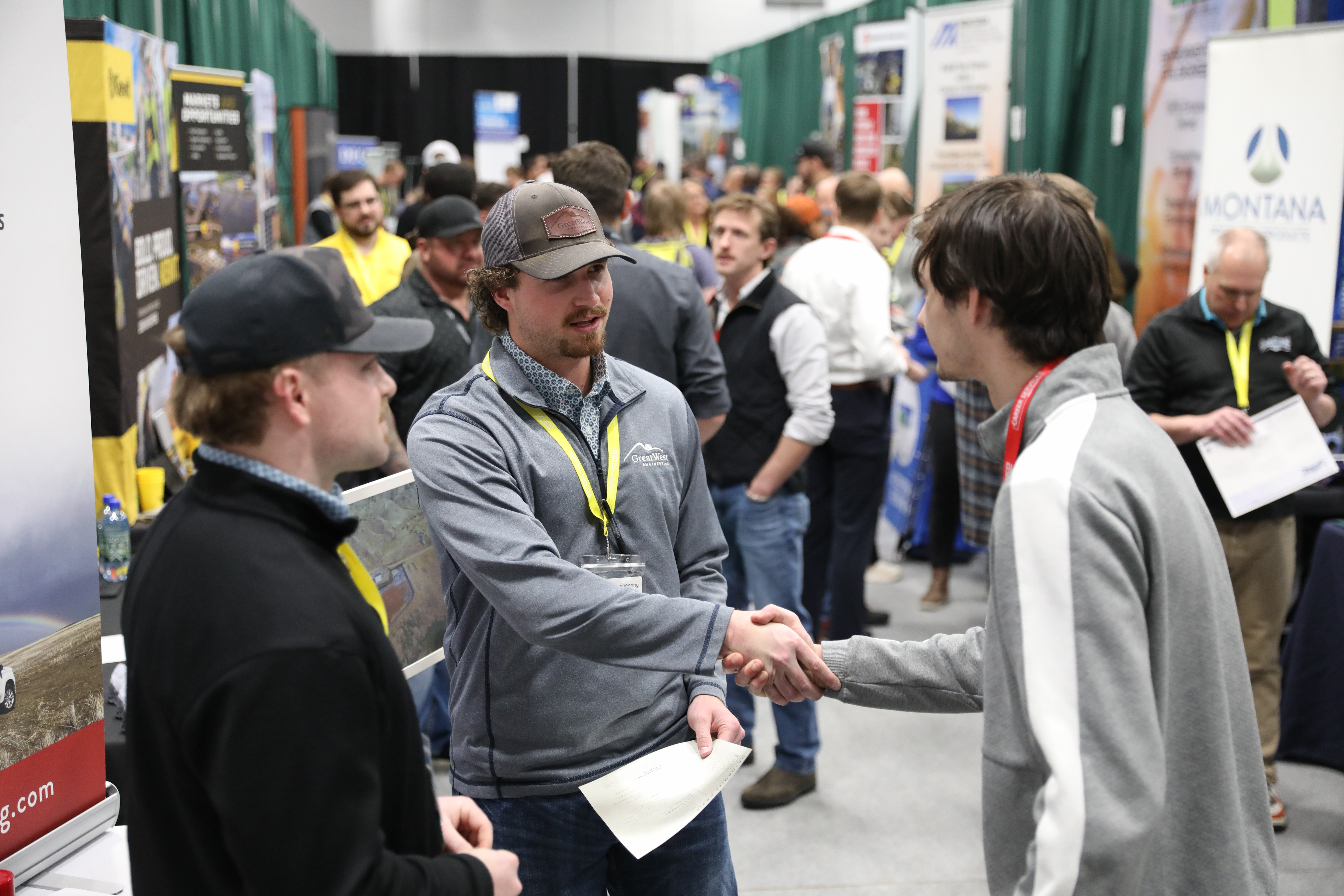 People handshaking at a career fair event.