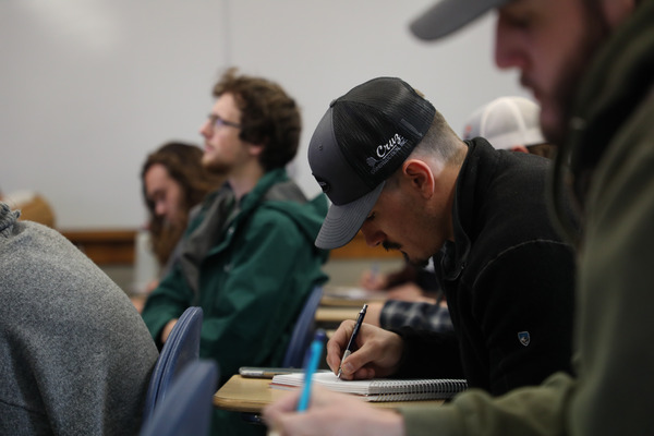 Students writing in notebooks during class.
