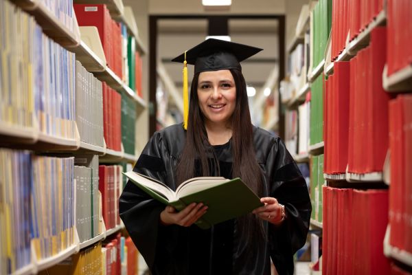!Eva Andrade Barahona in the library in her cap and gown