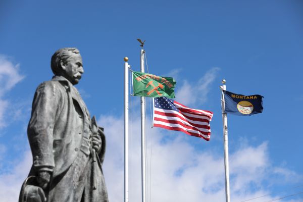 !Marcus Daly statue with flags flying behind