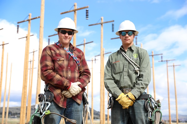 !Two Montana Tech line students pose for a photo in the pole yard