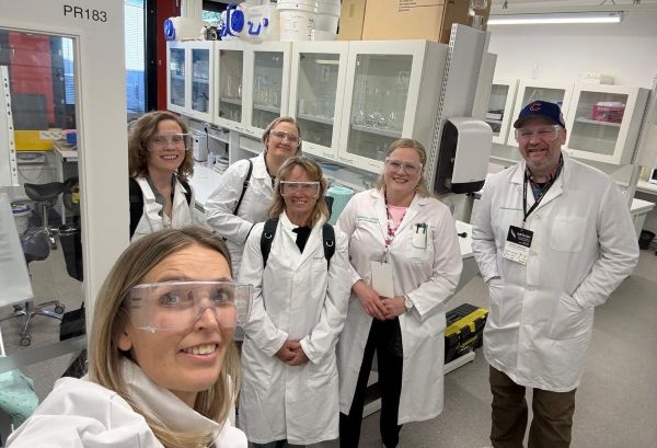 !Six people in labcoats in a laboratory setting