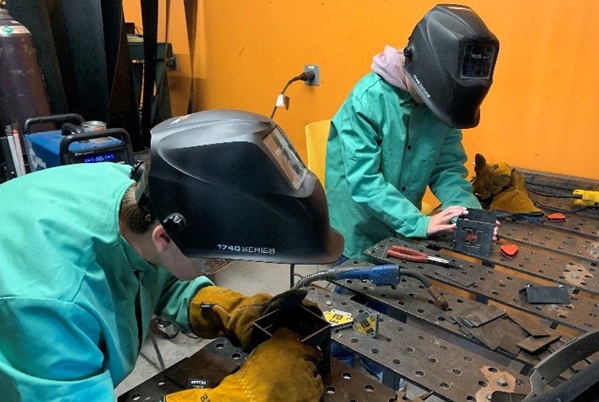 !2 students work in welding helmets